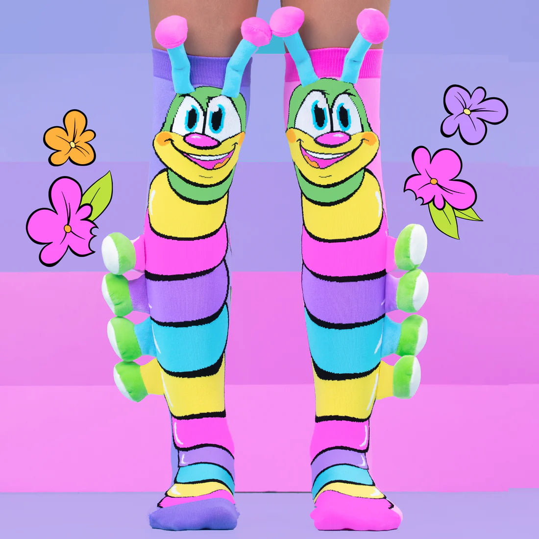 Colorful Madmia brand caterpillar-themed socks on a person against a purple and pink background with flowers.