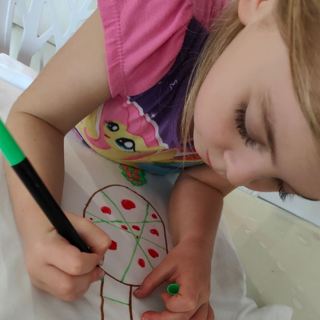Permanent Markers being used to decorate a blank white ts-shirt